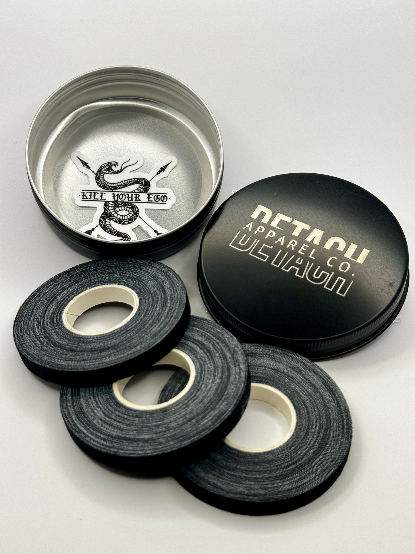Three rolls of finger tape and metal tin